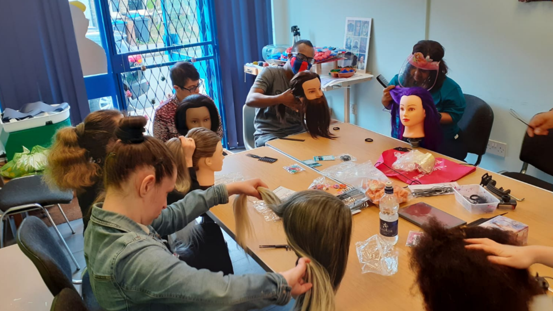 Photo of group of people learning hair styling with mannequins