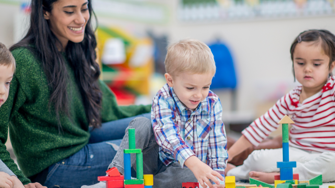 Photo of woman sitting down with very young children playing