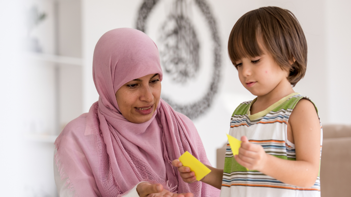 Photo of a woman in a hijab teaching a young child