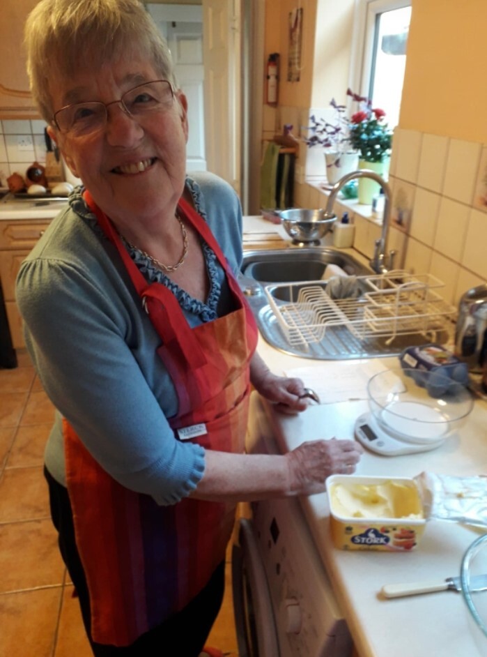 Nan cooking in kitchen wearing red apron 